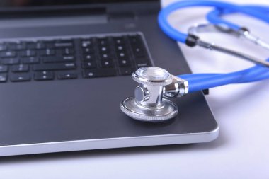İşyeri dizüstü bilgisayar, stetoskop, Rx reçeteli, gözlük ve beyaz masa üstünde defter doktor. Kopya alanı.
