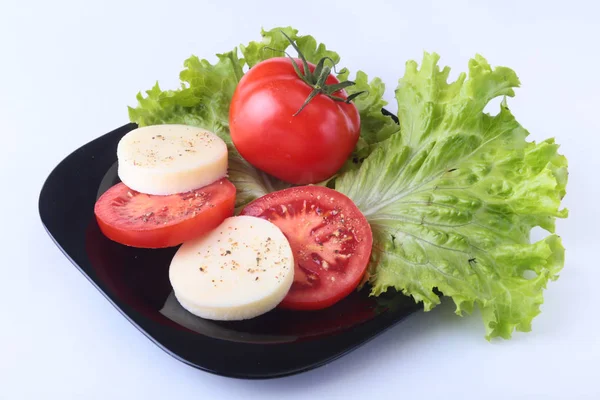 Порция моцареллы с помидорами, листом салата и бальзамическим соусом на черной тарелке. селективный фокус крупным планом . — стоковое фото