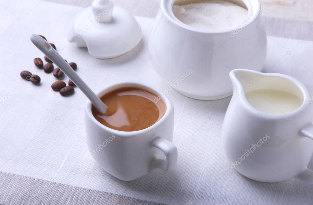 Cup of hot coffee espresso, coffee beans, jug of milk, and bowl with sugar on white background for copy space. Coffee concept.