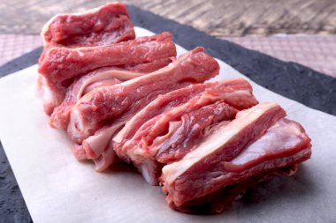 Çiğ taze et, pişmemiş kuzu veya dana kaburga biber, sarımsak, tuz ve baharat karanlık taş zemin üzerine hazır yemek pişirmek için. kopya alanı.