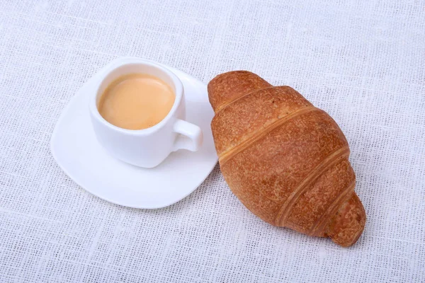 Klassieke espresso in witte kop en croissant op witte achtergrond. Bovenaanzicht. — Stockfoto