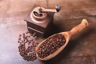 kahve çekirdekleri bir ahşap kepçe ve karanlık taş masada Kahve değirmeni.