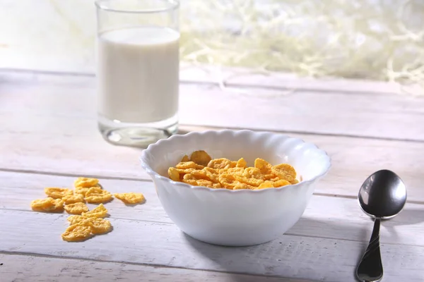 Copos de maíz cereales en un tazón y un vaso con leche. Desayuno por la mañana . —  Fotos de Stock
