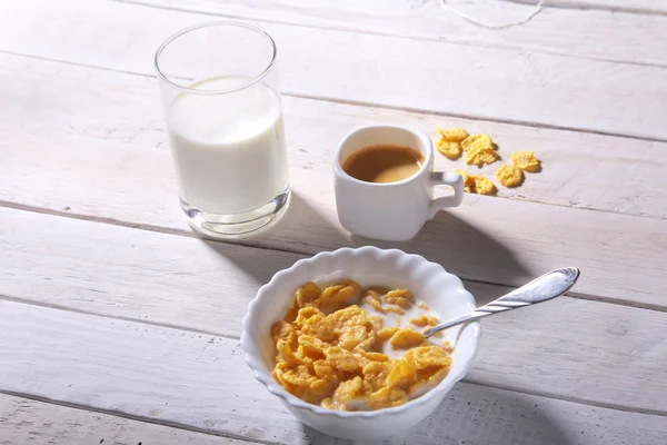 Corn Flakes cereal in a bowl, glass with milk and cap with espresso coffee. Morning breakfast. — Stock Photo, Image