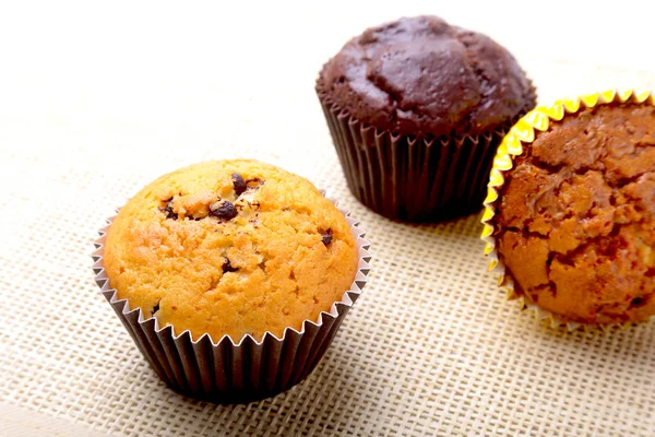 Assorted with Delicious homemade cupcakes with raisins and chocolate isolated on textile background. Muffins. Top view. — Stock Photo, Image