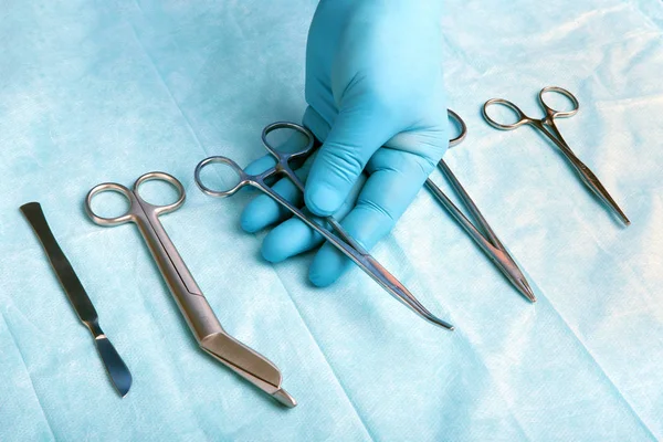 Detalle plano de instrumentos de cirugía esterilizada con una mano agarrando una herramienta  , — Foto de Stock