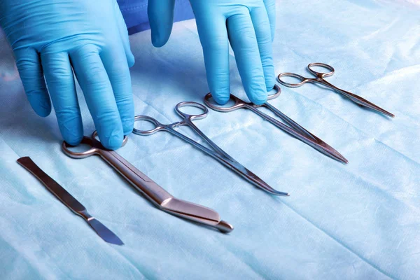 Detalle plano de instrumentos de cirugía esterilizada con una mano agarrando una herramienta  , — Foto de Stock