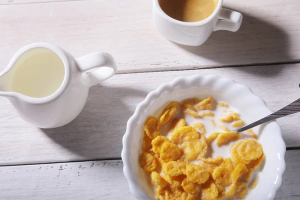 Καλαμπόκι νιφάδες δημητριακών σε ένα μπολ, γυαλί με γάλα και καπάκι με καφέ espresso. Πρωινό το πρωί. — Φωτογραφία Αρχείου