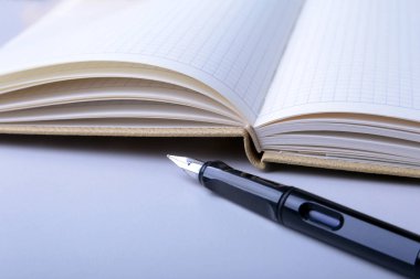 İş amaçlı aksesuarları üstünde okul sırası: Not Defteri, günlük, dolma kalem, gözlük. Makro bulanıklık ve yumuşak odak ile.