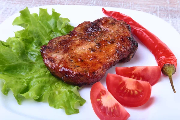 Steak z grilovaného masa a chilli s rajčaty, salátových listů na bílé plotně. — Stock fotografie