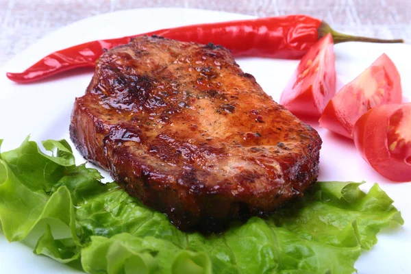 Steak daging panggang dan cabai dengan tomat, daun selada di piring putih . — Stok Foto
