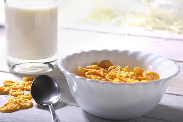 Copos de maíz cereales en un tazón y un vaso con leche. Desayuno por la mañana . —  Fotos de Stock