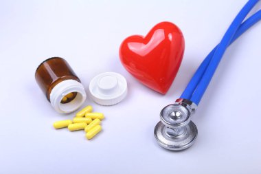Stetoskop, kırmızı kalp ve metin için yer ile beyaz tabloda çeşitli hap.