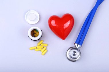 Stetoskop, kırmızı kalp ve metin için yer ile beyaz tabloda çeşitli hap.