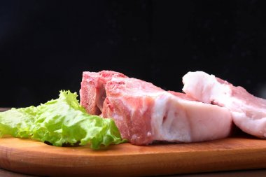 Tuz, biber ve baharat değirmeni ile bir rustik kesme tahtası üzerinde çiğ biftek. Kopya alanı için siyah arka plan. Üstten Görünüm.