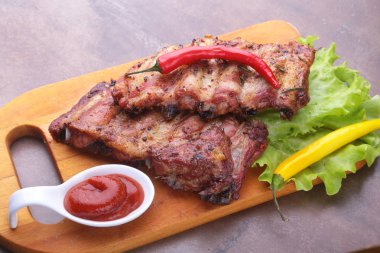 marul yaprakları, sıcak biber ve sos ahşap kesme tahtası üzerinde mangalda kaburga ızgara.