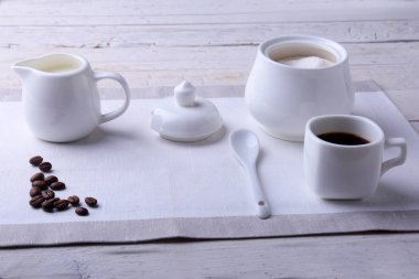 Bir fincan sıcak kahve espresso, kahve çekirdekleri, sürahi süt ve şeker kopya alanı için beyaz arka plan üzerine bir kase. Kahve kavramı.