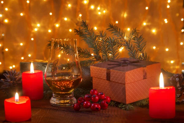 Vaso con coñac o whisky, bolas de Navidad y velas sobre fondo de iluminación borrosa. Árbol de Año Nuevo, bolas y vidrio con alcohol. Felices fiestas decoración . —  Fotos de Stock