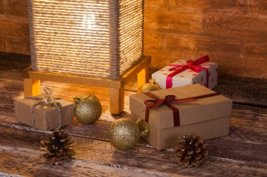 Klasik masa lambası, hediye kutuları ve ahşap arka planda renkli Noel topları. Tatil zamanı..