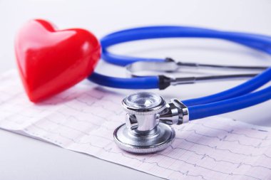Tıbbi steteskop ve kırmızı kalp kardiyogramda yakın planda yatıyor. Tıbbi yardım, prezervatif, hastalık önleme ya da sigorta konsepti. Kardiyoloji.