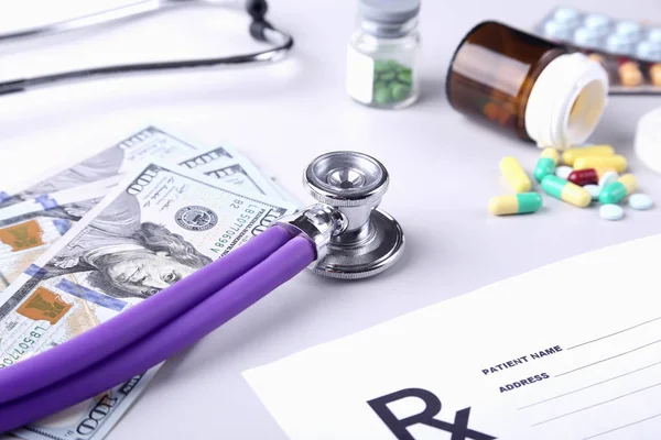 Tabletten, Dollarnoten und Stethoskop liegen in Großaufnahme auf dem Kardiogramm-Diagramm. Behandlungskosten und Bezahlungskonzept für das Gesundheitswesen. Kardiologische Versorgung. — Stockfoto