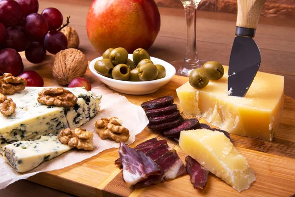 Assortiment de fromage avec fruits, raisins, noix, verre avec vin et couteau au fromage sur un plateau de service en bois. Images De Stock Libres De Droits