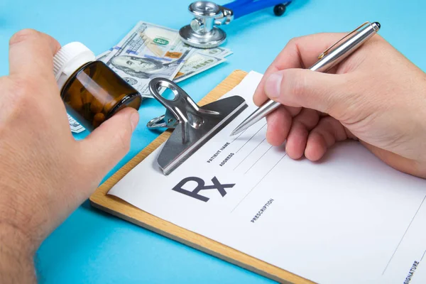 Médico masculino ou farmacêutico segurando frasco ou frasco de pílulas na mão e escrevendo prescrição em um formulário especial. custos médicos e conceito de pagamento de cuidados de saúde . — Fotografia de Stock