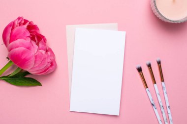 Makyaj fırçalı beyaz kart ve pembe arka planda güzel çiçek şakayığı. Anneler günü ve tatiller.
