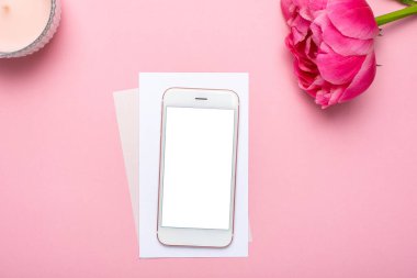 Cep telefonu modeli ve pembe pastel masa üzerindeki şakayık çiçeği düz yatıyordu. Masada çalışan bir kadın. Yaz rengi