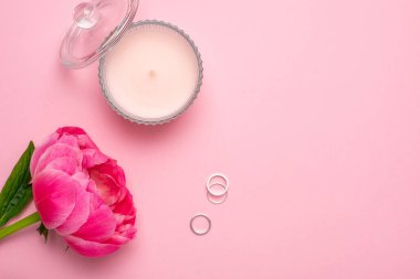 Güzel kadınların dairesi öncü çiçeklerle, mumlarla ve yüzüklerle kaplıydı. Pastel pembe arka plan üzerine yazınız için kopyalama alanı vardı. Moda yaz rengi..