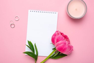 Güzel pembe şakayık çiçeği ve pastel pembe arkaplan üzerine yazdığın metin için kopya alanı olan bir defter.