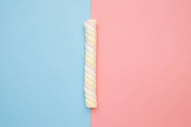 Pembe ve mavi arka planda renkli uzun marşmelovlar, leziz tatlılar düz uzanıyordu.