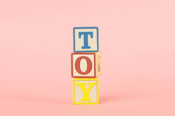 Colored cubes with letters with the inscription Toy on a pink background