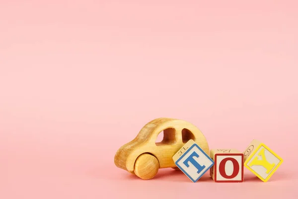 Розовый фон с цветными кубиками с буквами игрушка и игрушка автомобиль — стоковое фото