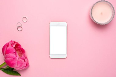 Cep telefonu modeli ve pembe pastel masa üzerindeki şakayık çiçeği düz yatıyordu. Masada çalışan kadın. Rengi