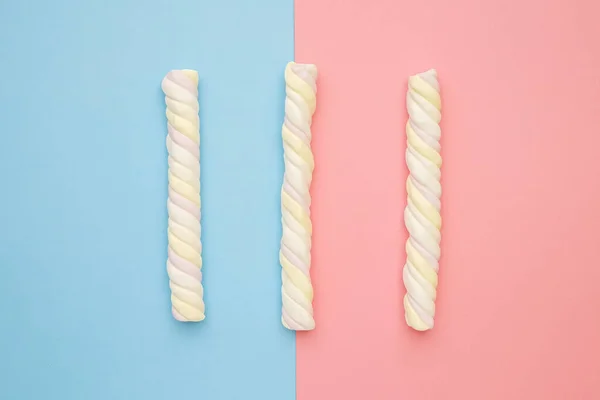 Farbige lange Marshmallows auf rosa und blauem Hintergrund, köstliche Süßigkeiten flach gelegt — Stockfoto