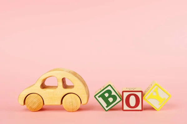 Цветные кубики с буквами Мальчик и автомобильная игрушка на розовом фоне — стоковое фото