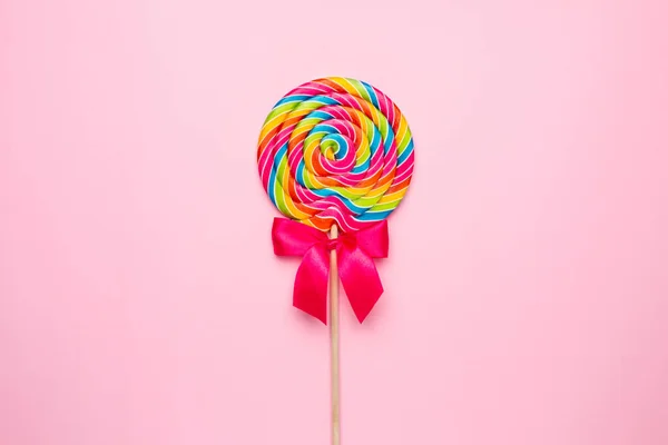 Espiral de piruleta colorida con palo de madera sobre fondo rosa, dulces infantiles — Foto de Stock