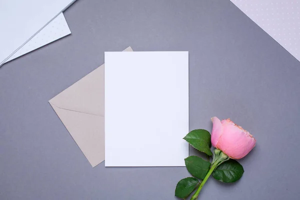 Dárková karta a obálka s růžovou růží na šedém pozadí — Stock fotografie