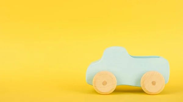 Κίτρινο φόντο με παιδικό μπλε παιχνίδι αυτοκινήτου και copyspace — Φωτογραφία Αρχείου