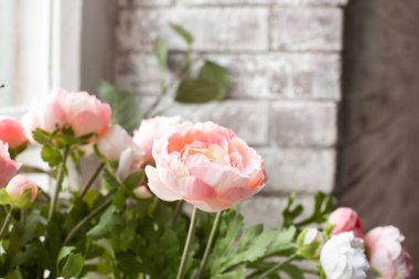 Beyaz tuğlalı bir duvarın arka planında suni pembe çiçekler