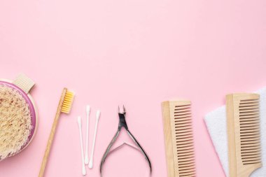 Ahşap diş fırçası, tarak ve meme uçlarıyla pembe arka plan, banyo ve kaplıca aksesuarları