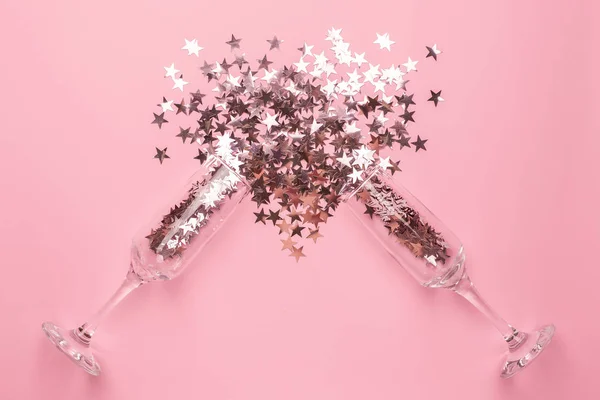 Copas de champán con estrellas de color rosa plateado confeti sobre papel de color rosa estilo minimalista — Foto de Stock
