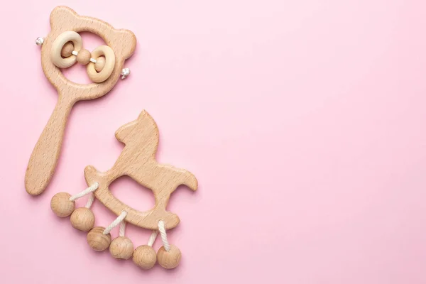 Bebek ahşap çıngıraklar ve pembe arka plandaki oyuncaklar kopya alanı ile izole edilmiş.