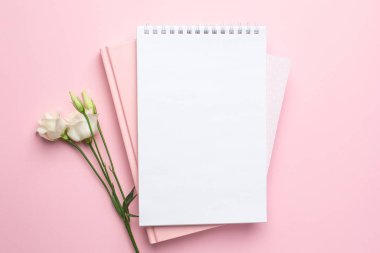 Güzel beyaz Eustoma çiçeği ve pembe arka planda bir defter.