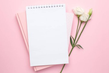 Güzel beyaz Eustoma çiçeği ve pembe arka planda bir defter.