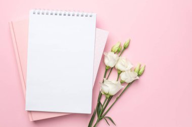 Güzel beyaz Eustoma çiçeği ve pembe arka planda bir defter.