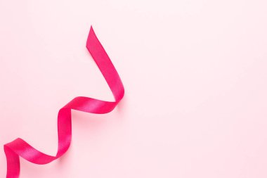 Pembe arka planda hediye kurdele fuşya rengi. Tatiller için minimalist kompozisyon.