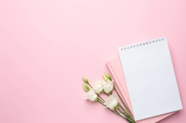 Pembe arka plan, güzel beyaz Eustoma çiçeği ve defter. Kopyalama alanı olan düz alan