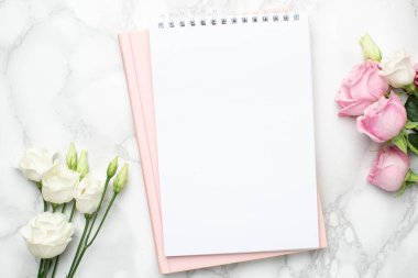 Güzel beyaz ve pembe güller çiçek ve mermer arka planda defter